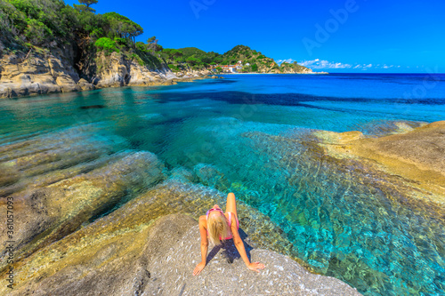 Foto Woman in pink swim suit resting and sunbathing in Cotoncello Beach near popular Sant 'Andrea beach, Elba island