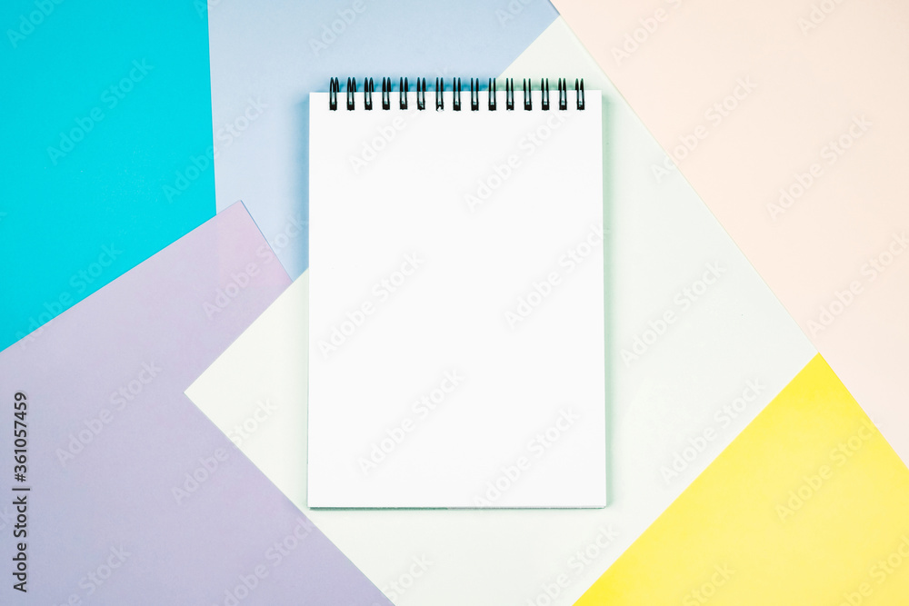 Notepad with a blank white sheet on a colorful geometric background. Notepad with a blank white sheet on a colorful geometric background.