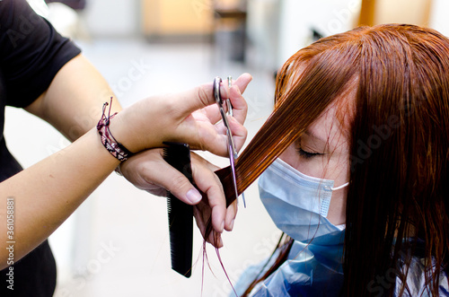 Mujer pelirroja cortándose el pelo con la mascarilla puesta