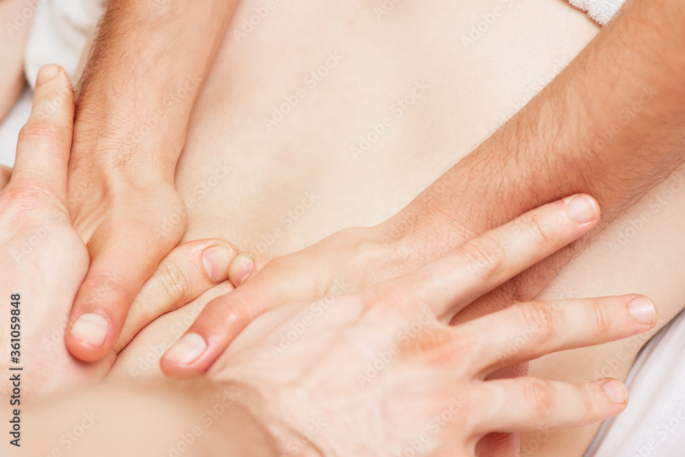 Woman receiving back massage with four hands of two male therapists close up. Woman receiving back massage with four hands of two male therapists close up.