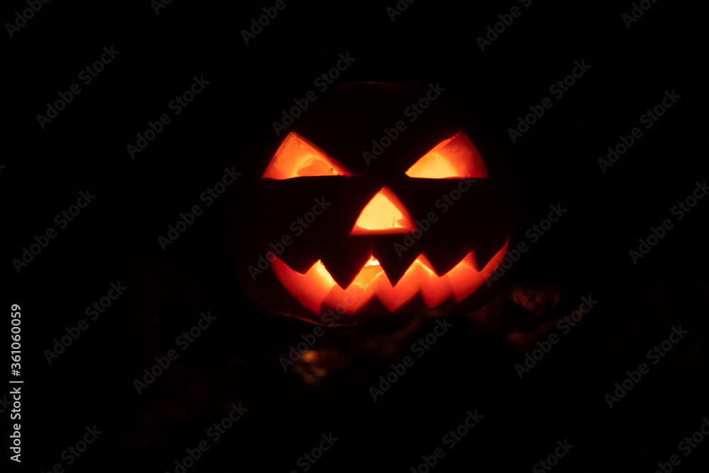 Glowing eyes and mouth of a pumpkin in complete darkness close-up. Beautiful Halloween background, concept. Glowing eyes and mouth of a pumpkin in complete darkness close-up. Beautiful Halloween background, concept.