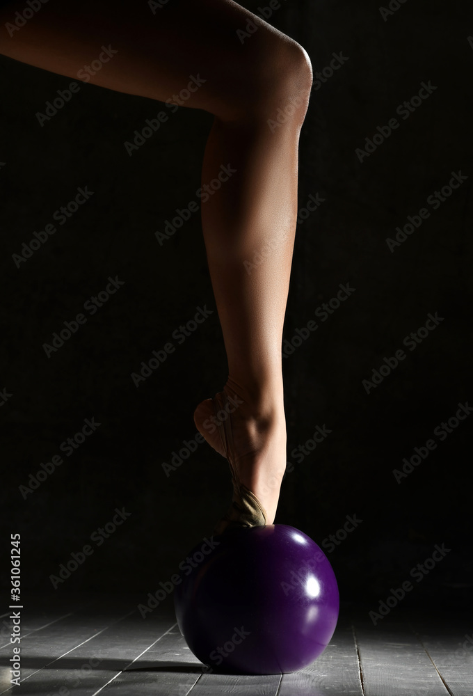 Rhythmic gymnastics concept. Sport woman hands and legs closeup composition stretching fitness exercises workout with purple ball