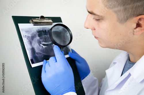 A dentist doctor examines a radiography of the teeth of a patient who has problems and teeth are inserted. The concept of research and diagnosis photo
