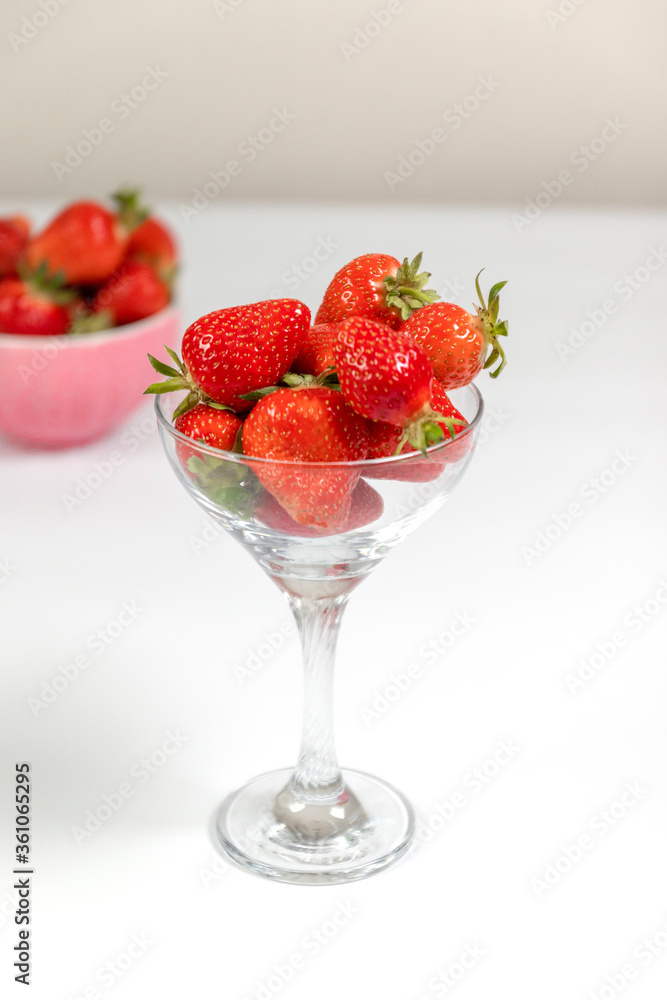 Strawberry berries in a glass goblet on white background by the window. Summer concept Strawberry berries in a glass goblet on white background by the window. Summer concept