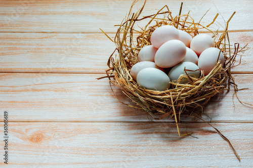White eggs in hay nest on wooden table background