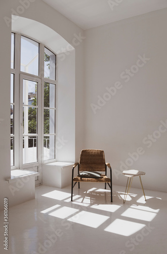 Empty white sunny room with wicker chair and table. Minimalist design