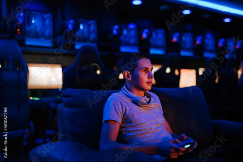 Enjoying playing games.Portrait of a young man playing game with joystick at internet cafe.