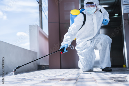 Canvas Print Man in virus protective suite and mask spraying alcohol cleaning covid19 infecte