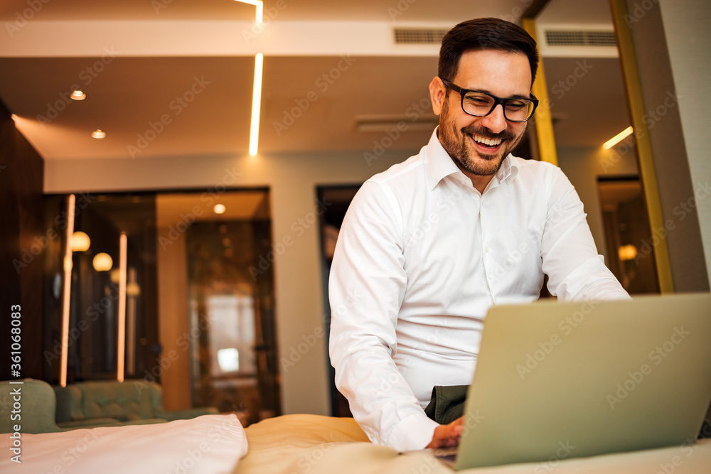 Happy elegant man using laptop on the bed, in the hotel room, portrait.Close-up, low angle image. Happy elegant man using laptop on the bed, in the hotel room, portrait.Close-up, low angle image.
