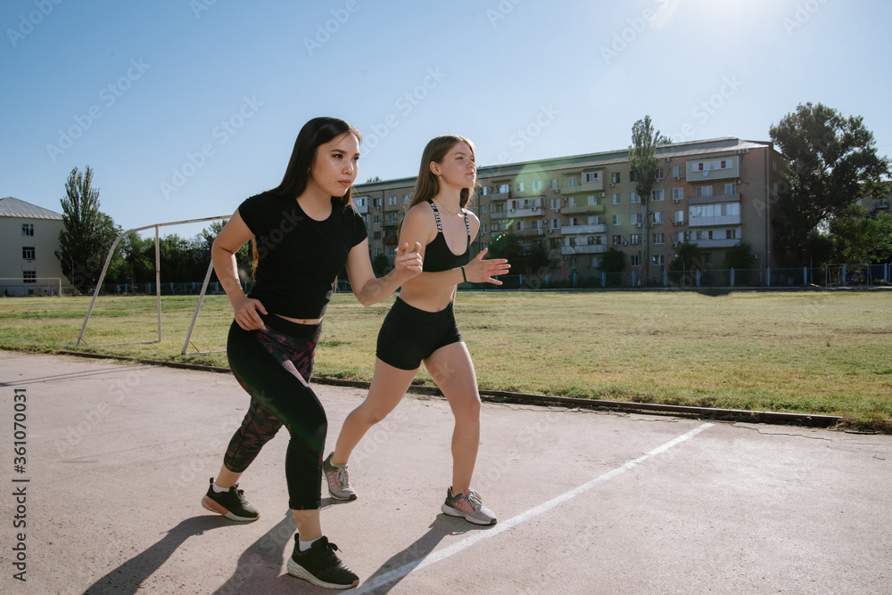 Two athletes at the starting position in the stadium. Athletic girls run in the stadium Two athletes at the starting position in the stadium. Athletic girls run in the stadium