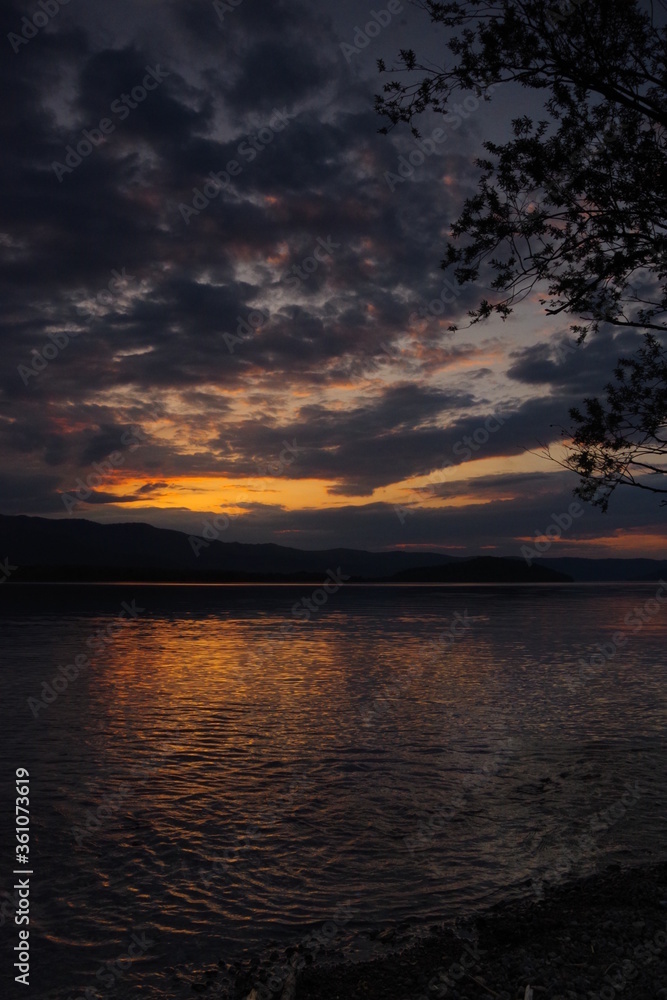 黄昏時の空と湖の風景。雲の漂う夕暮れの空と夕陽に煌めく湖面。屈斜路湖、北海道、日本。
