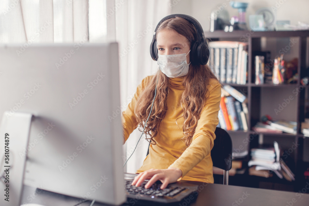 Teen gaming at home with computer, wearing protective mask Teen gaming at home with computer, wearing protective mask