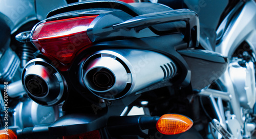 Exhaust pipes and brake light of a motorcycle closeup. The noise of a sports bike in a garage. Rear view of a classic road bike. A pair of chrome pipes selective focus. Banner for web site