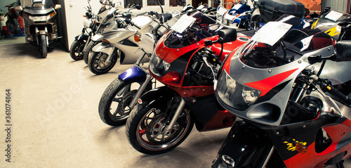Colored sports, road beautiful bikes in a motor show. Many motorcycles parked in a store. Sale of used cruise motorbikes in the cabin. Showroom equipment in the garage. Banner for web site