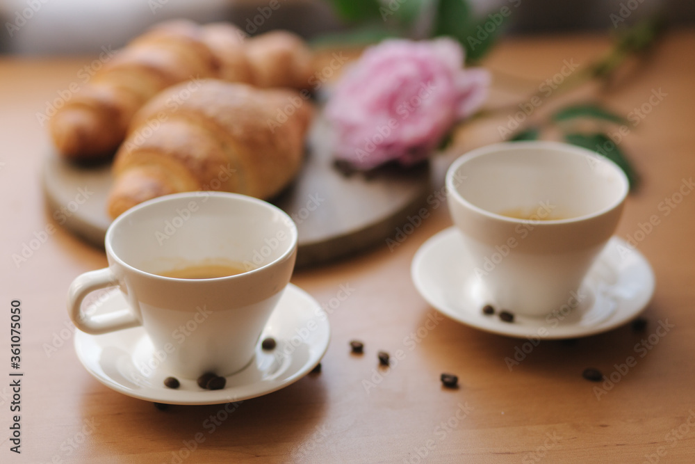 Vegan breakfast at home. Cappuccino with coconut milk and two empty vegan croissants. Morning with coffe. Pink peony flower on table Vegan breakfast at home. Cappuccino with coconut milk and two empty vegan croissants. Morning with coffe. Pink peony flower on table