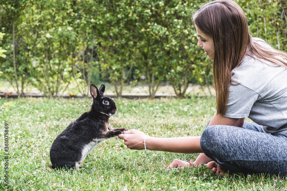 Teenager girl playing with her black rabbit in the garden Teenager girl playing with her black rabbit in the garden