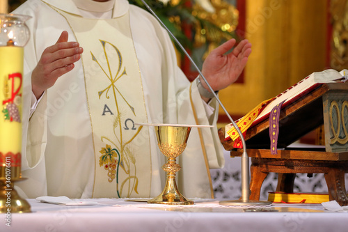 Fotografía Chalice on the altar and priest celebrating mass in the background