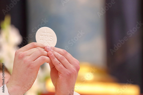 Canvas Print Holy host in the hands of the priest on the altar during the celebration of the