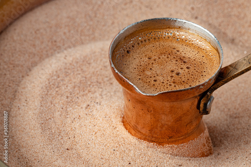 Copper turk with coffee brewing in sand photo