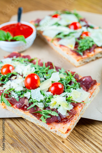 pizza with cherry tomatoes, parmesan cheese, arugula and smoked ham