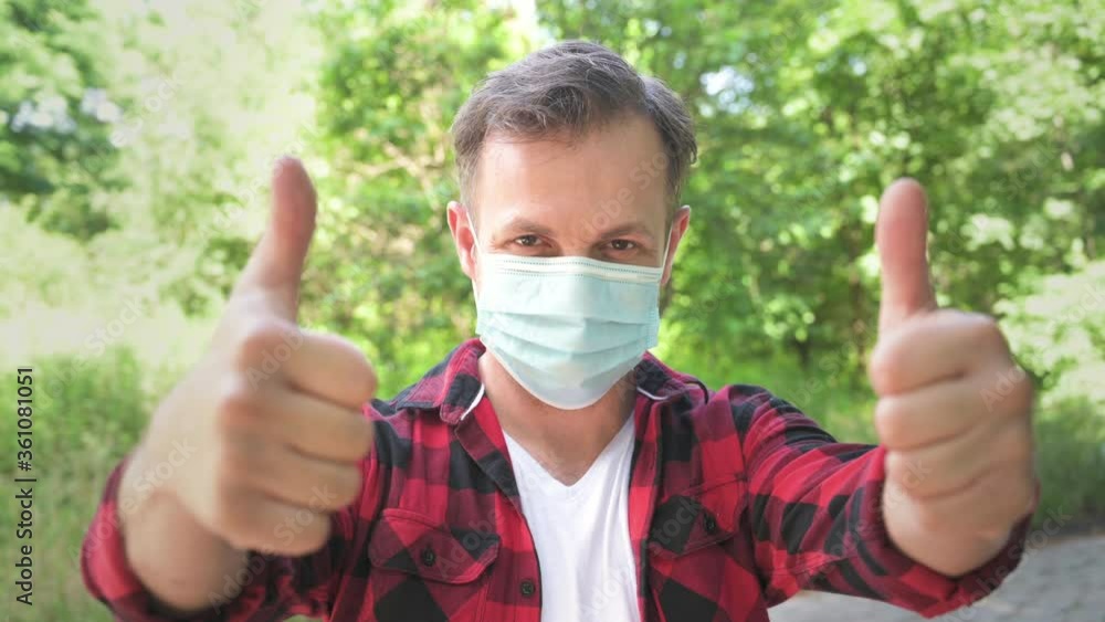 Happy caucasian man in medical protective face mask looking at camera and showing thumbs up gesture. Coronavirus prevention. Portrait of male at green background. Concept of covid 19. Happy caucasian man in medical protective face mask looking at camera and showing thumbs up gesture. Coronavirus prevention. Portrait of male at green background. Concept of covid 19.