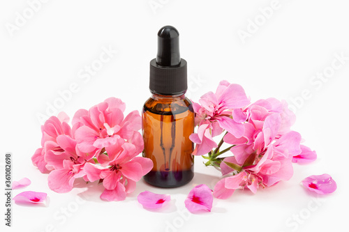Geranium essential oil on amber bottle isolated on white background. Herbal oil