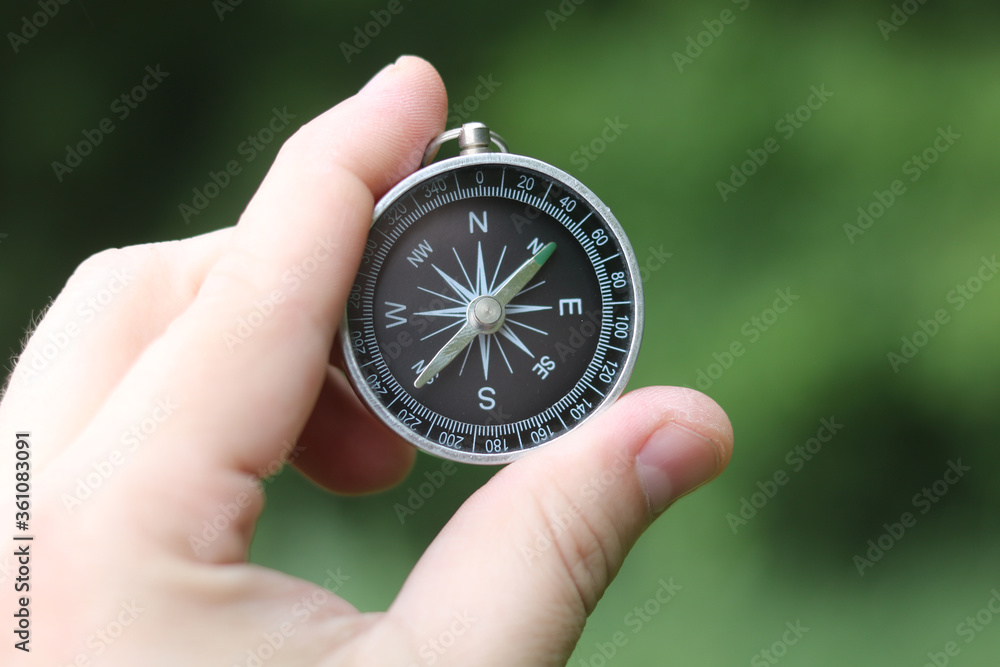Old classic navigation compass in hand on natural background as symbol of tourism with compass, travel with compass and outdoor activities with compass Old classic navigation compass in hand on natural background as symbol of tourism with compass, travel with compass and outdoor activities with compass