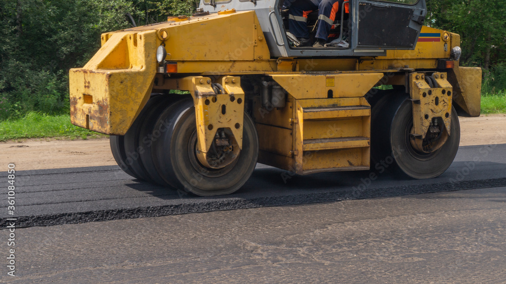 Close-up asphalt roller machinery. Road repair works on the suburb highway Close-up asphalt roller machinery. Road repair works on the suburb highway