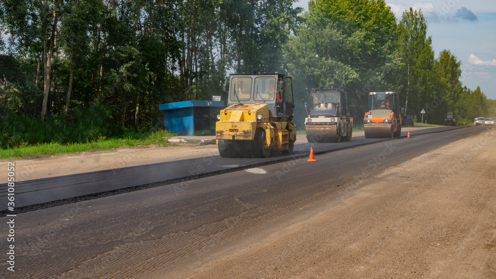 Rollers paving asphalt. Road repair works on the suburb highway