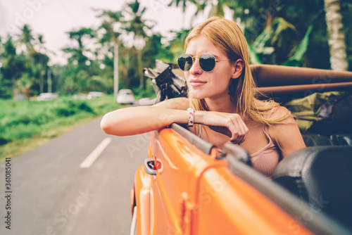 Pensive woman resting while transporting by cabriolet looking at scenic natural environment during roadtrip,dreamy hipster girl in sunglasses enjoying traveling on vacations renting automobile