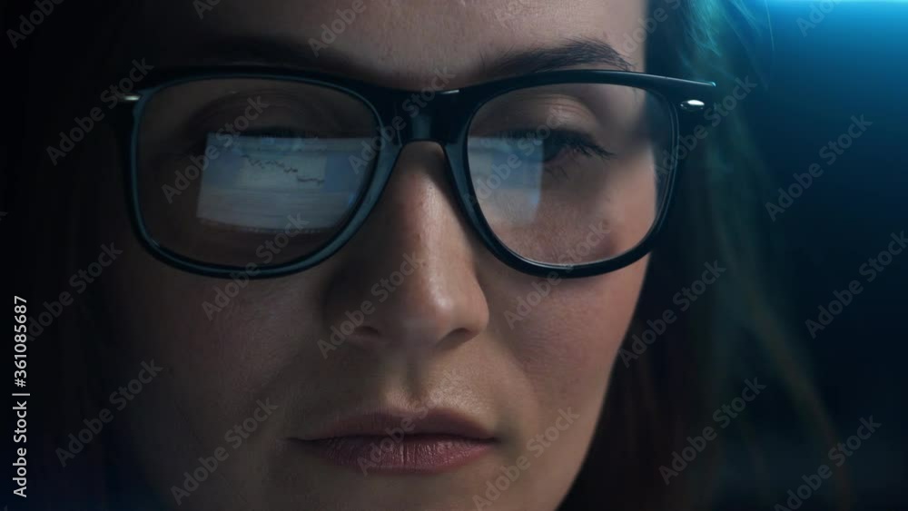 Close up of tired woman working at night on laptop, girl in eye glasses with reflections overworking busy, using computer in dark office Close up of tired woman working at night on laptop, girl in eye glasses with reflections overworking busy, using computer in dark office