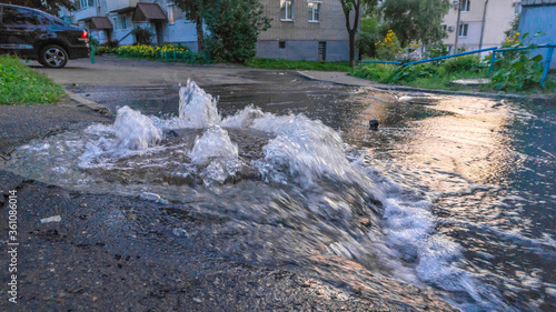 Dirty sewage water flows fountain on road from sewer manhole