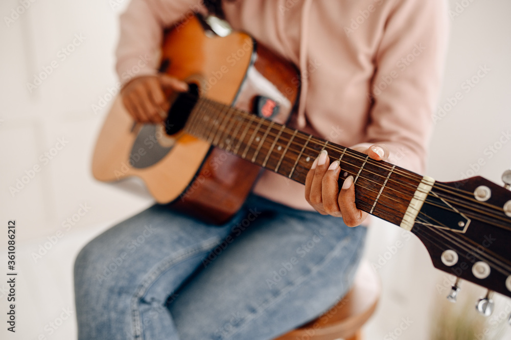 Woman play the guitar at home, closeup view