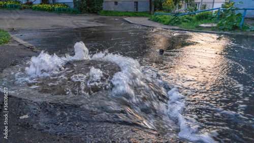 Overflowing Manhole cover with flood water pouring out.