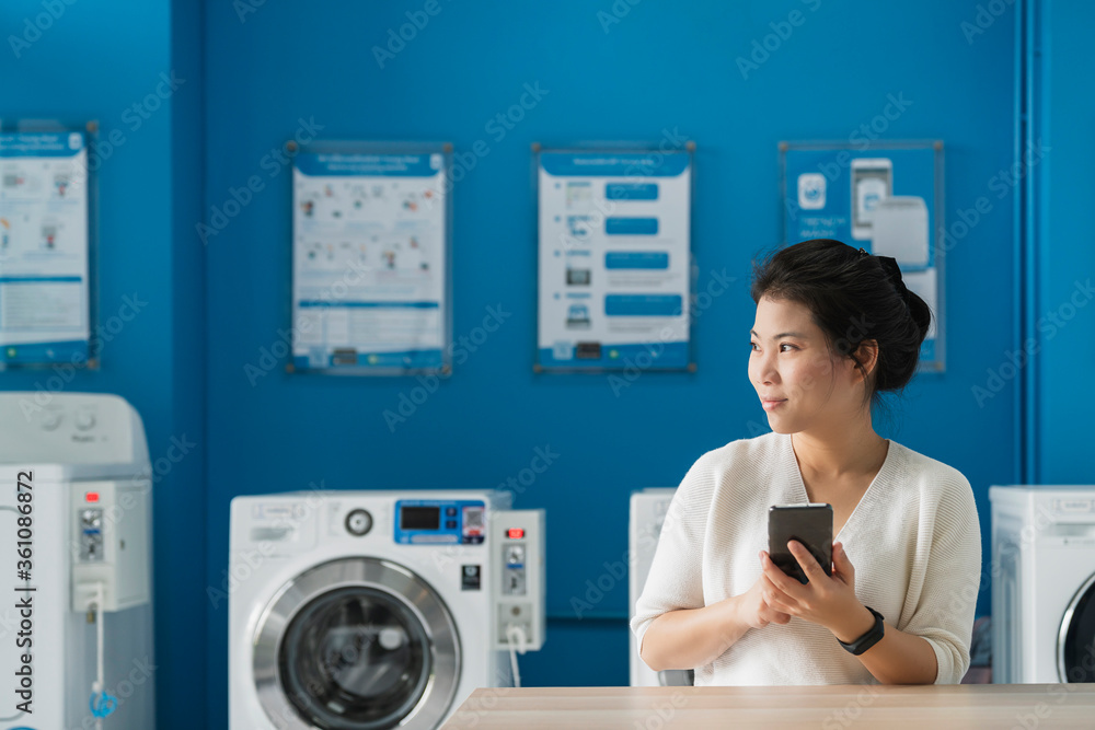 portrait asian female hand use smartphone to check schedule of washing queue in blue color interior laundry shop in condoiminuim city lifestyle portrait asian female hand use smartphone to check schedule of washing queue in blue color interior laundry shop in condoiminuim city lifestyle