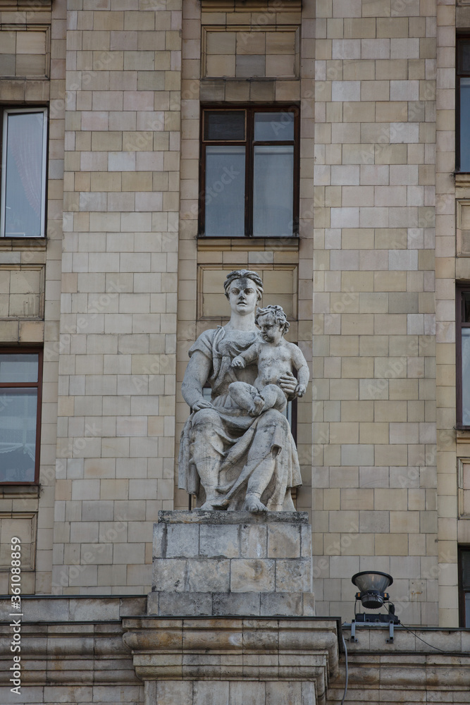 MOSCOW / RUSSIA - 20/04/2019 soviet communist stone sculpture of a sitting mother holding a baby child (sculptors Baburin, Nikogosyan, Anikushin) Kudrinskaya Square Building (Aviators' House) facade