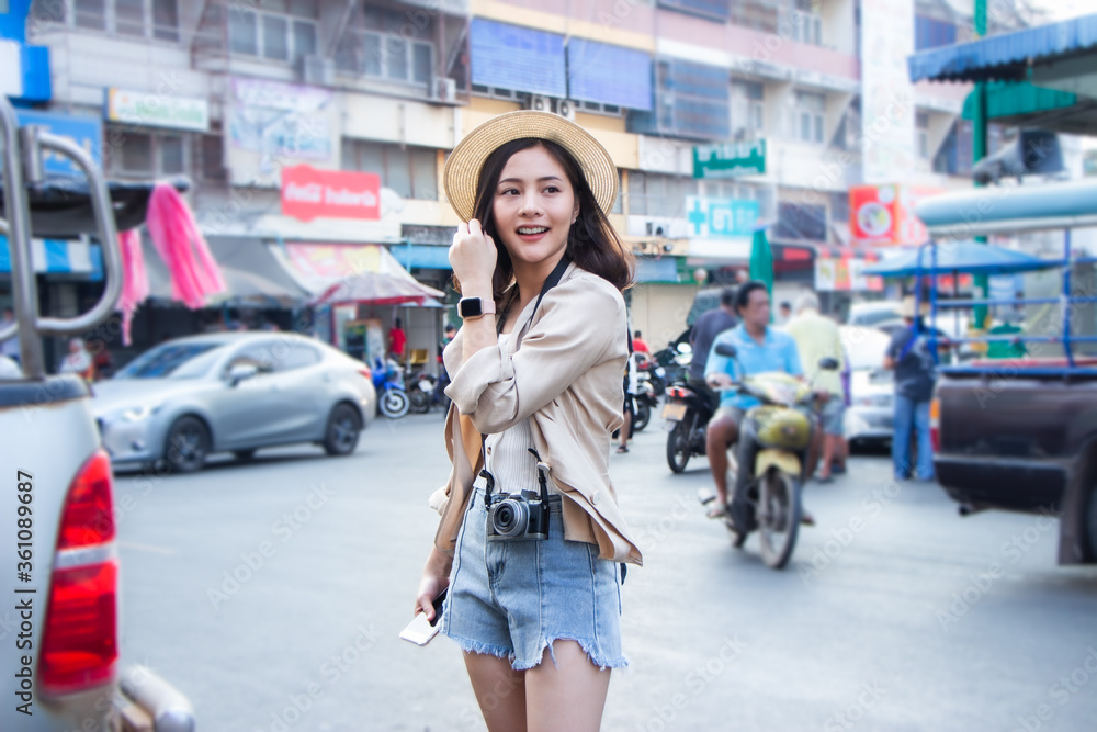 Fototapeta premium asia female tourists wearing hat holding camera and smartphone take photo vlog live. Beautiful woman take taxi boat visiting Damnoen Saduak floating market,Ratchaburi.