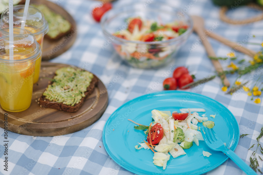 Woman take salad from blue plate on vegan picnic outdoors. Fresh and healthy food Woman take salad from blue plate on vegan picnic outdoors. Fresh and healthy food