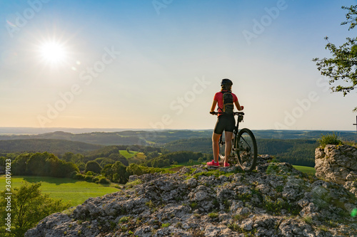 young woman admiring the awesome view over Frankonian Switzerland, during a mountain bike trip during golden hour in the evening photo