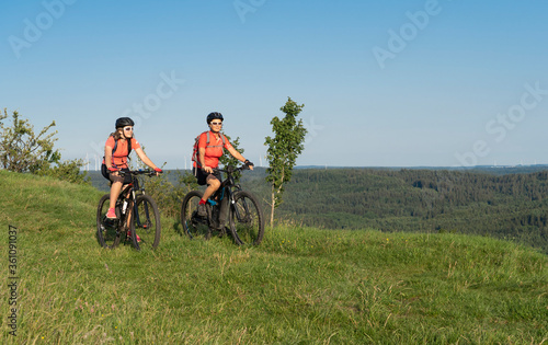 Grandmother with electric mountain bike and granddaughhter without electric help on a smooth meadow trail in the Franconian Switzerland area of Bavaria, Gemany © Uwe