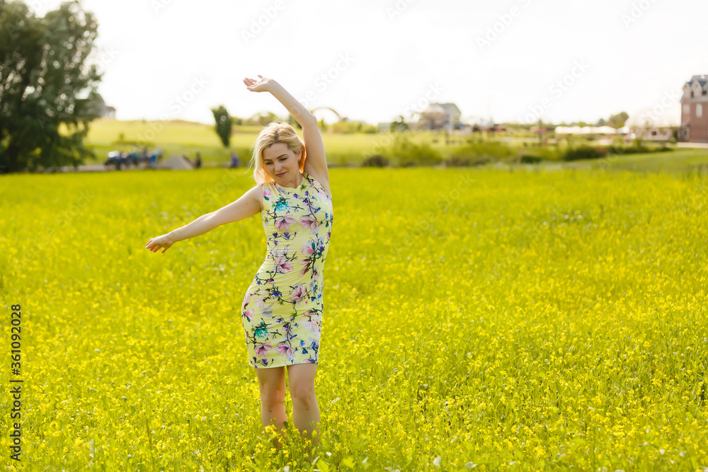 Young woman with her arms wide spread is enjoying in the sunny summer day, rear view Young woman with her arms wide spread is enjoying in the sunny summer day, rear view