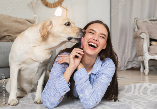 Young smiling woman with dog lying on floor