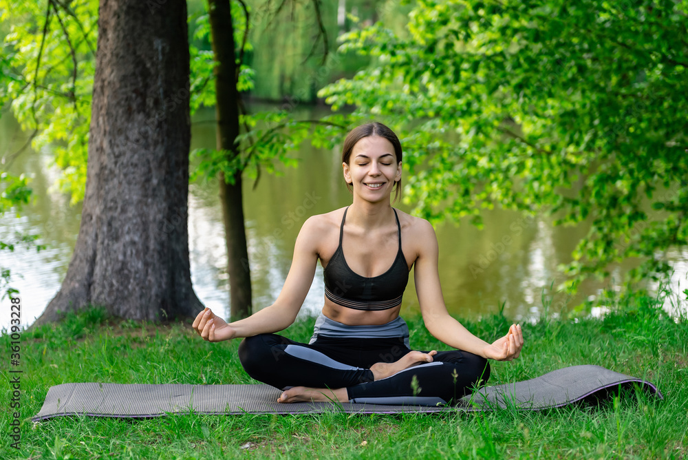 young girl sitting in lotus position on a yoga mat on summer nature young girl sitting in lotus position on a yoga mat on summer nature