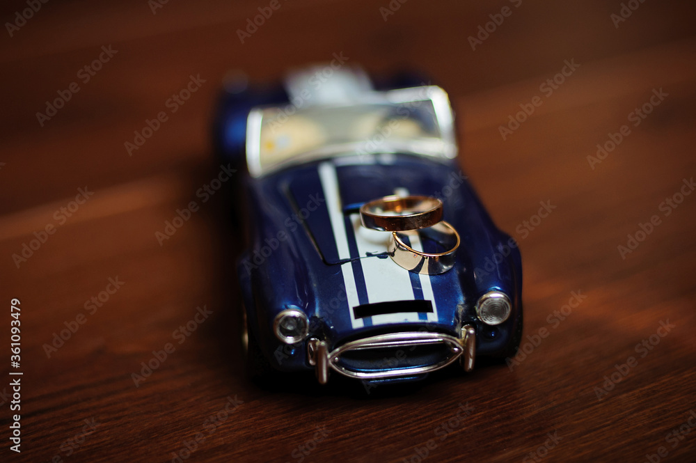 Golden wedding rings on a small toy retro car on a wicker chair made of wood. Macro, photography, concept. Golden wedding rings on a small toy retro car on a wicker chair made of wood. Macro, photography, concept.