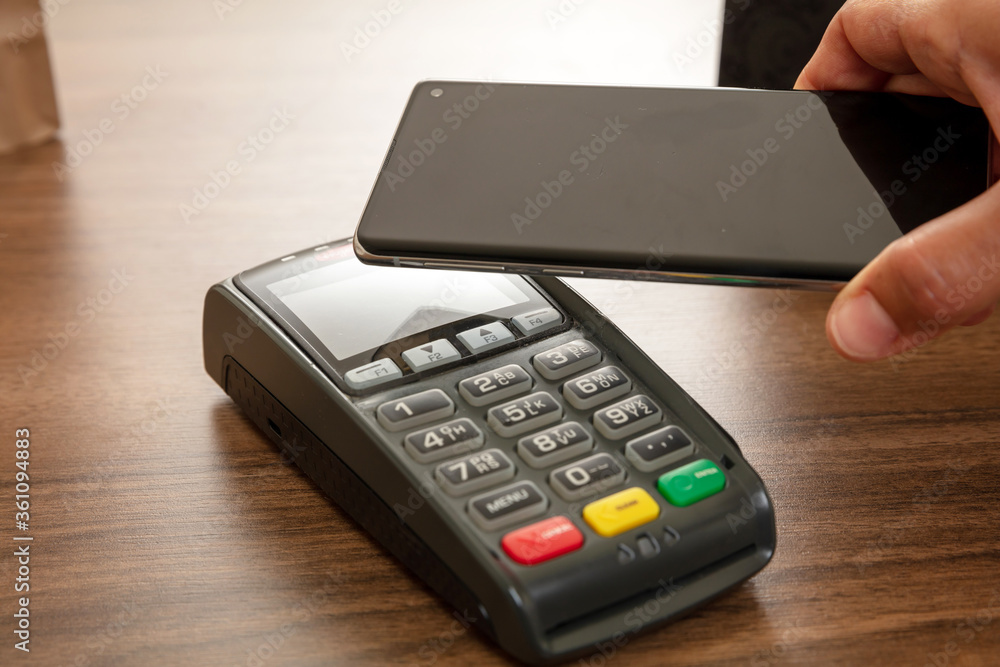 POS terminal for payment with smartphone, nfc technology. Customer hands closeup view POS terminal for payment with smartphone, nfc technology. Customer hands closeup view