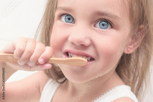 Little girl learns to brush her teeth. Dental care and health. Dental health concept  dentistry  hygiene. Bamboo toothbrush..Face close up.