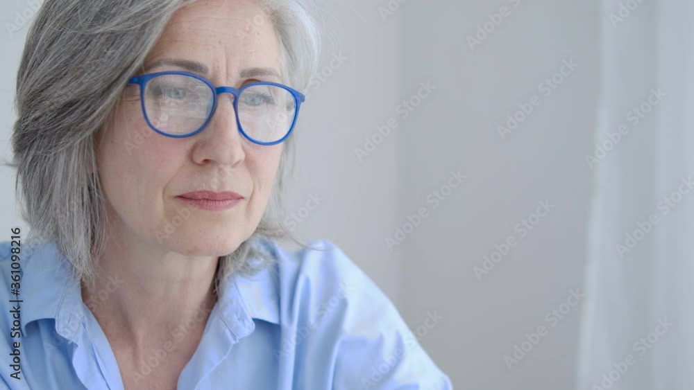 Sad mature woman dreaming remembering past times sitting near window, nostalgia Sad mature woman dreaming remembering past times sitting near window, nostalgia