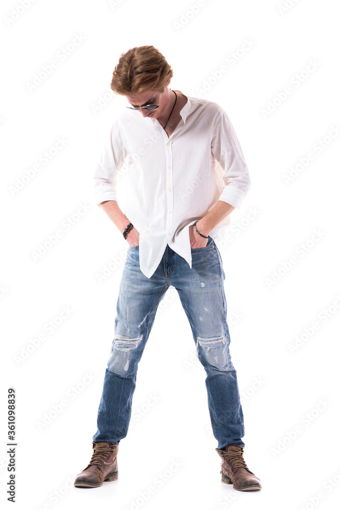 Fototapeta premium Young handsome man buying clothes trying on new jeans with hands in pockets. Full length portrait isolated on white background. 