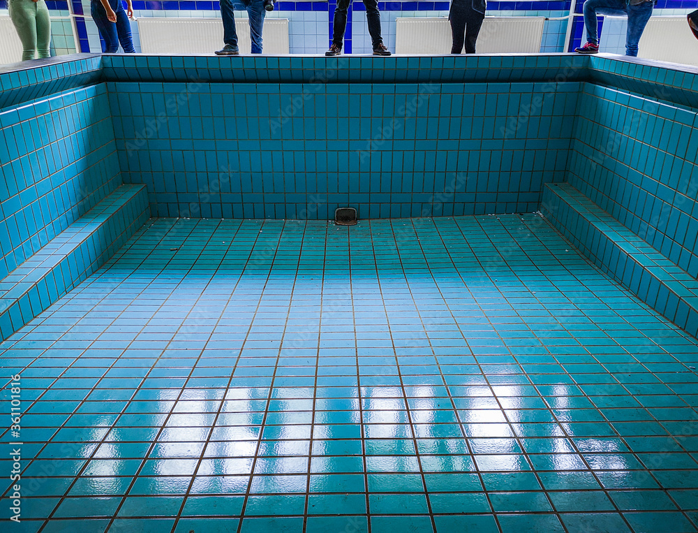 People standing on wall of empty swimming pool in old abandoned