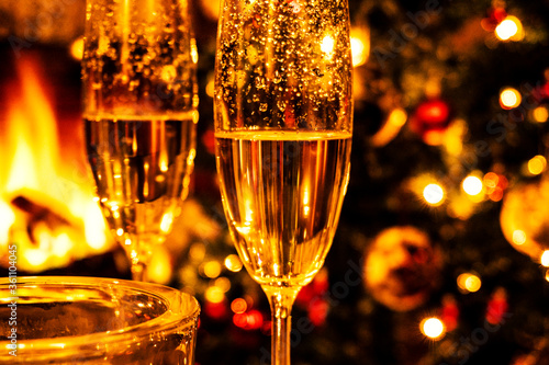 Champagne glasses on the background of Christmas tree and fireplace. New year celebration. Champagne glass close up.
